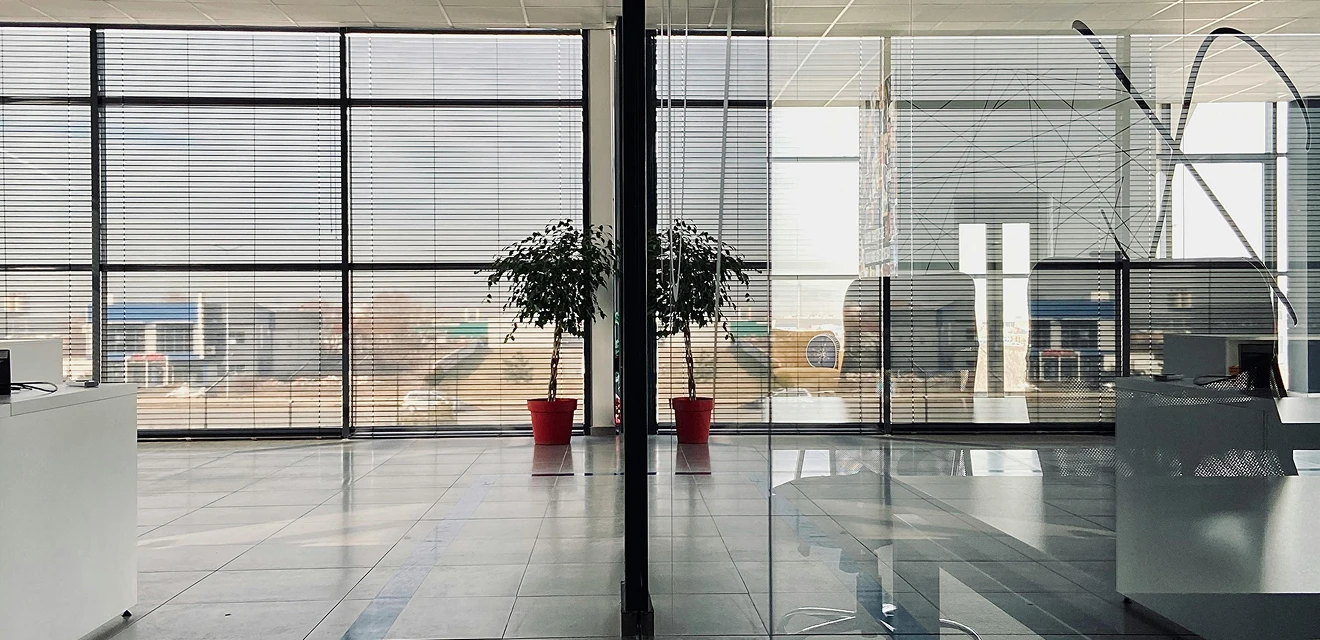 A modern office space with large windows featuring horizontal blinds.