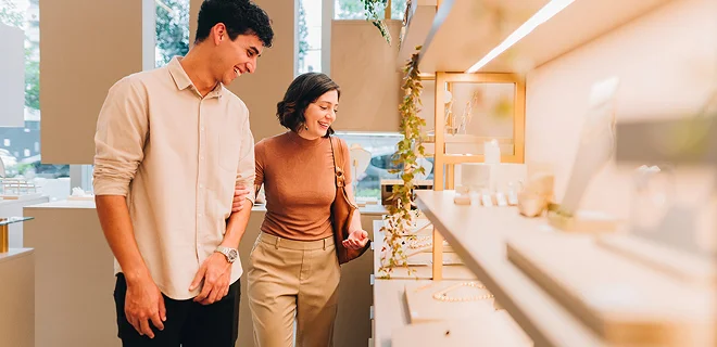 A couple is happily browsing a well-lit store display, examining products with interest. The atmosphere is warm and inviting.