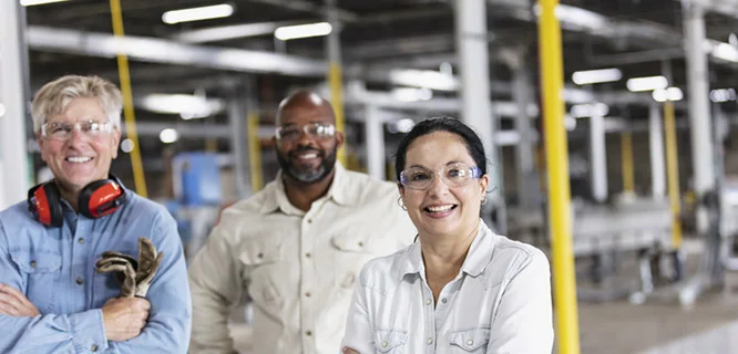 Workers in an industrial facitlity smiling at the camera.