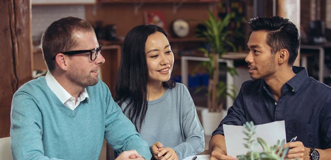 Three people smiling and discussing a business deal.