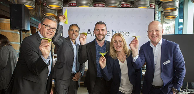 A group of business people posing for a photo holiding paper airplanes.