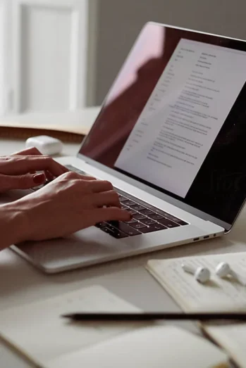 A person typing on a laptop, working on a document in a well-lit environment.