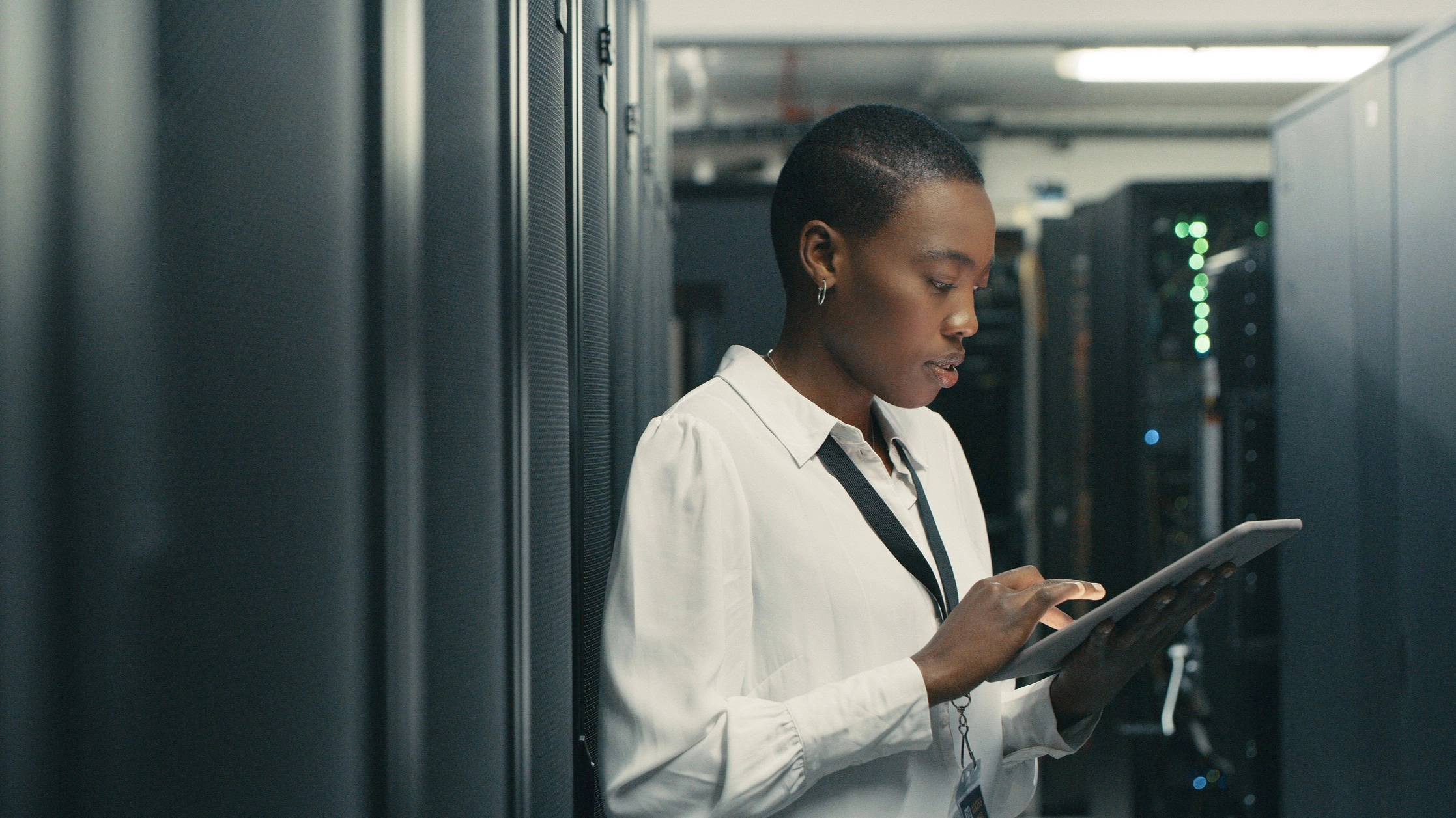 A person in a server room using a tablet.