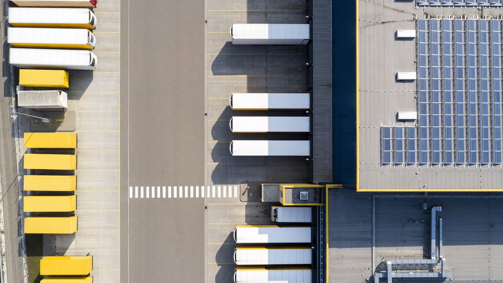 An aerial view of parked trucks and a building with solar panels.