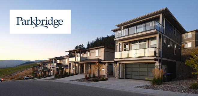 A modern, multi-story house with a glass-railed balcony and garage, situated in a residential neighborhood.