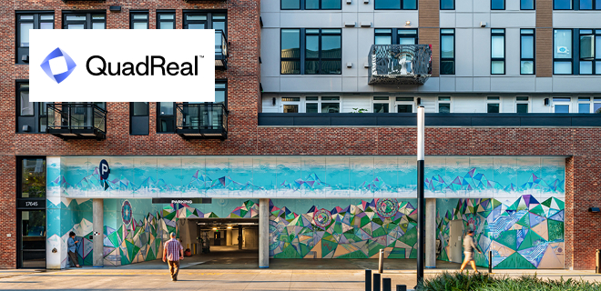 A building with mixed brick and modern paneling showcasing colorful murals on the lower level.