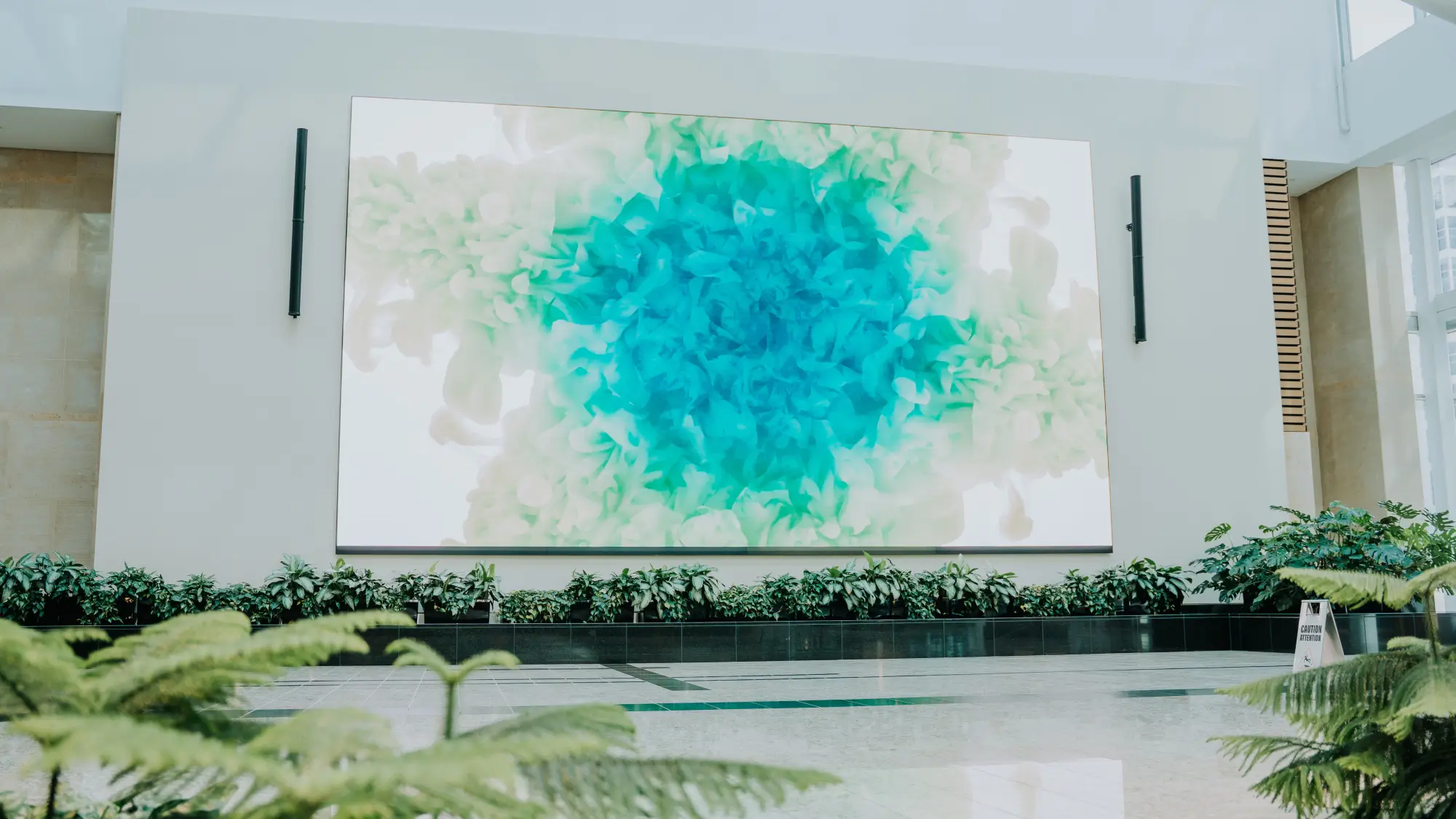 An abstract artwork in green and blue tones displayed on a large wall.