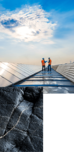 Deux travailleurs portant un équipement de sécurité inspectent des panneaux solaires sur un toit sous un ciel brillant et partiellement nuageux.