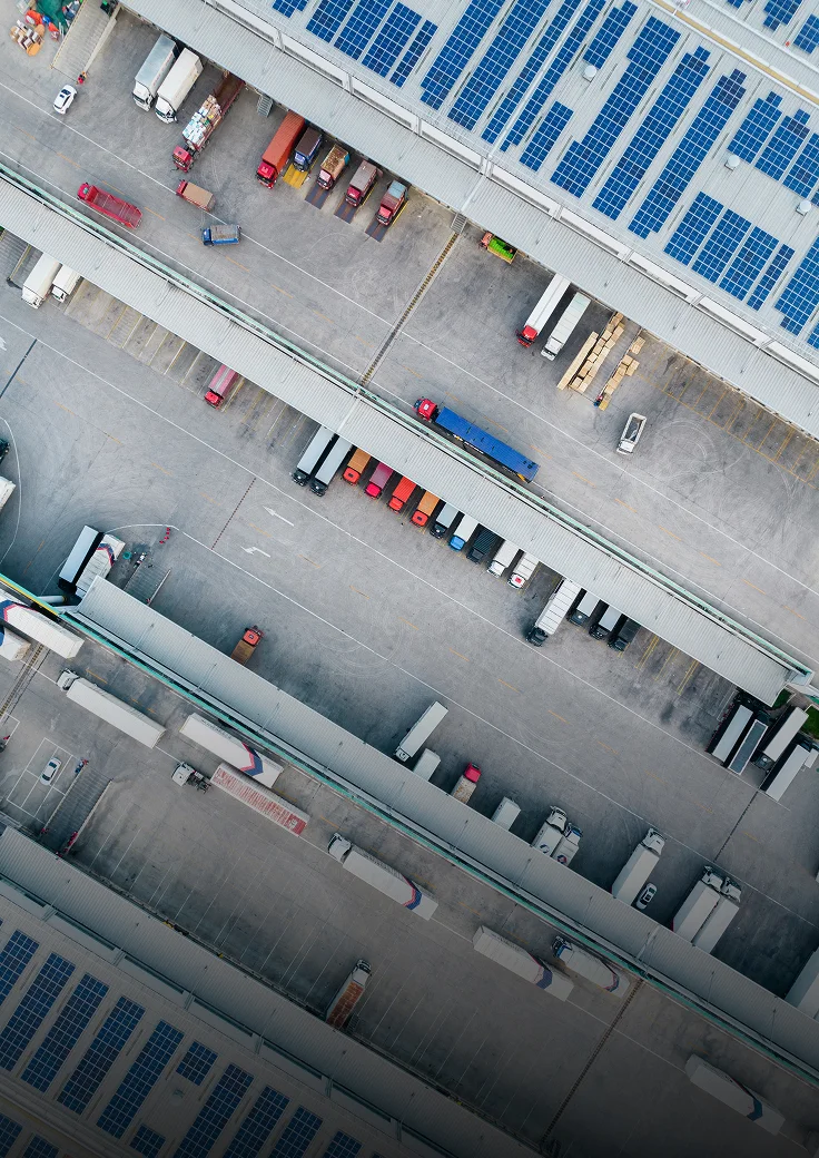 An aerial view of an industrial facility with trucks parked outside and solar panels on the roof.