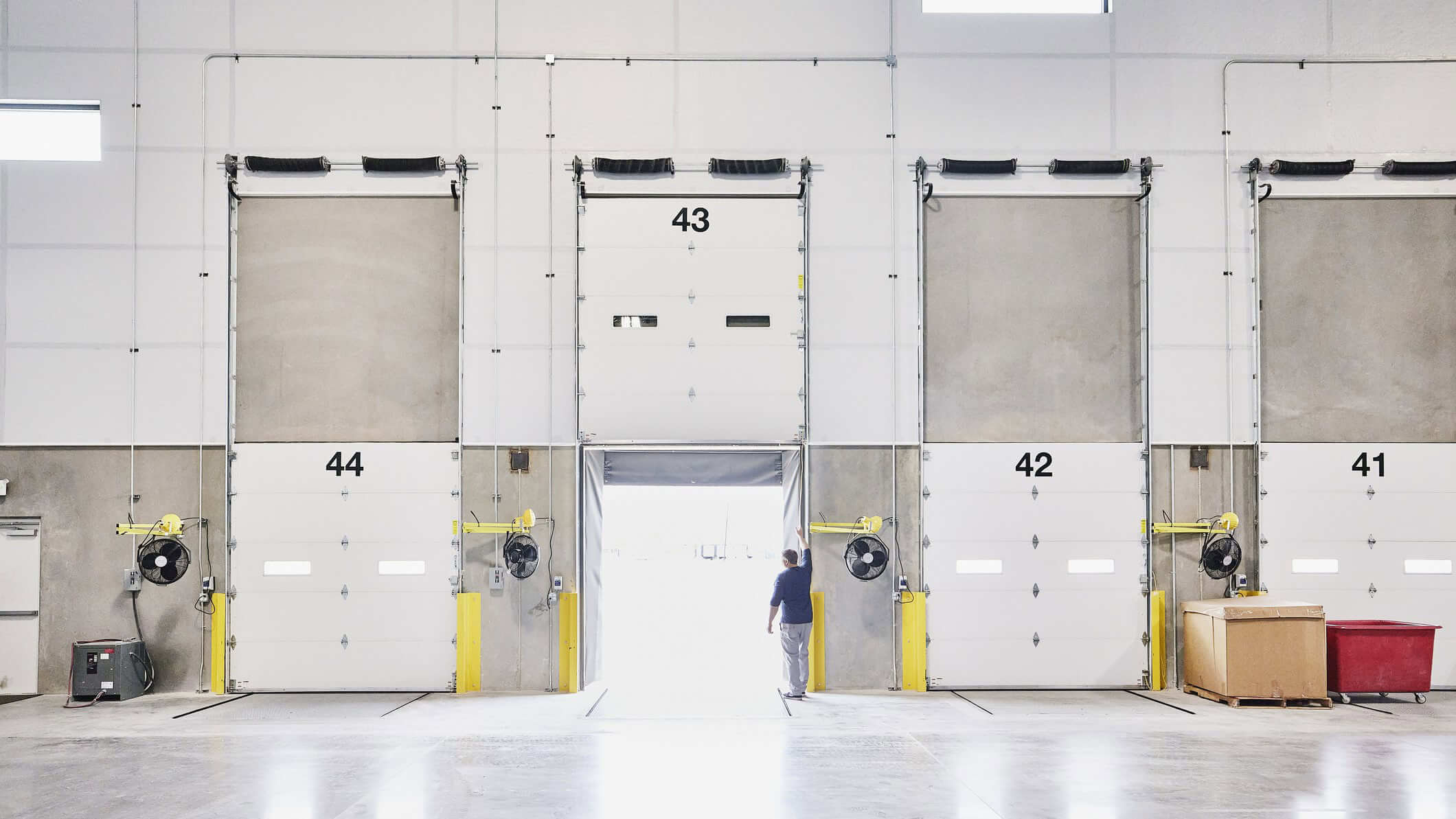 A row of industrial loading dock doors with yellow safety barriers.