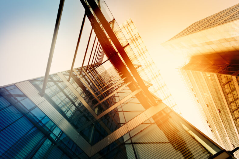 An abstract view looking up a glass walled building with sunlight.