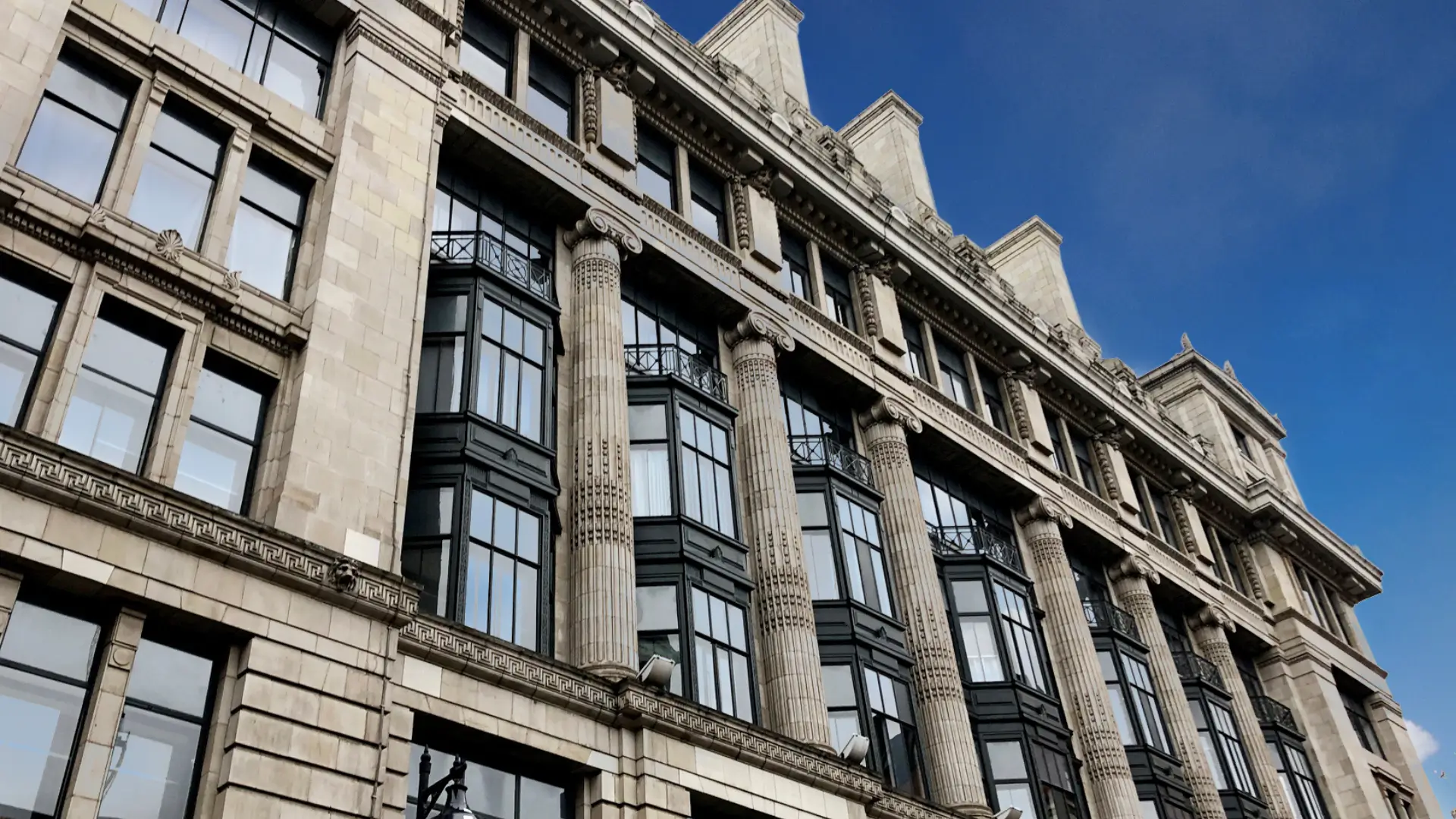 Classical-style building with bay windows and ornate stonework under a clear blue sky.