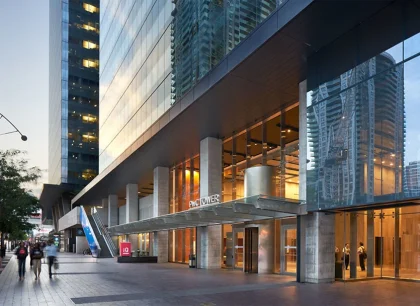 An exterior of a modern office tower with a warmly lit lobby.