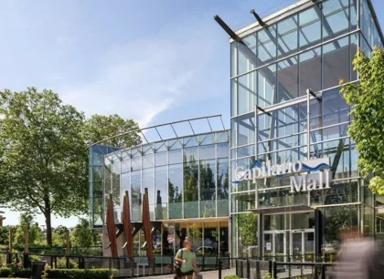 Bâtiment moderne avec une façade en verre entouré d’arbres, présentant un design architectural élégant.