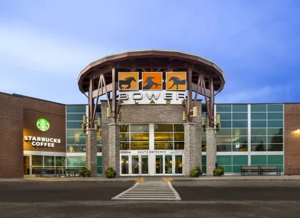 On the right, a modern shopping center with a rounded entrance and clear glass windows.