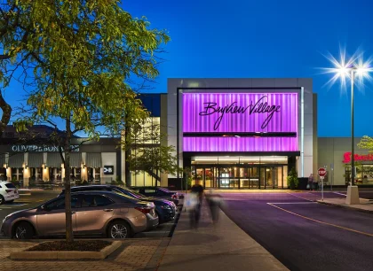 In the middle, a modern shopping complex illuminated at night with a brightly lit facade.