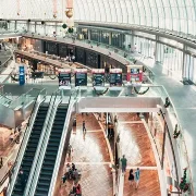 Vue sur l’intérieur d’un grand centre commercial ouvert avec des escaliers roulants menant à une mezzanine.