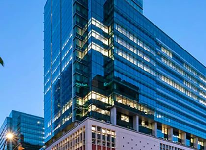 A modern glass tower viewed from a low angle at dusk.