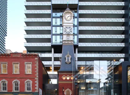 A historic clocktower sits in front of a modern residential building.